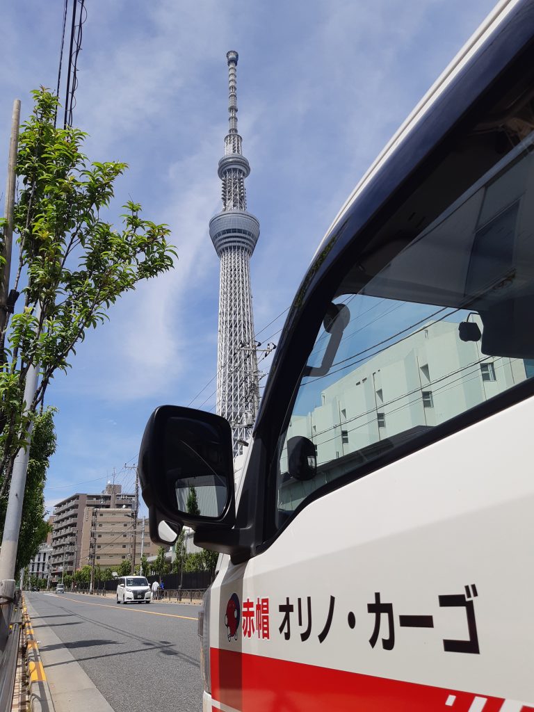 東京から群馬への引越し業務。引越し元の墨田区で作業開始時間まで待機中。東京スカイツリーと赤帽車。今日は女性の単身引越しです。
