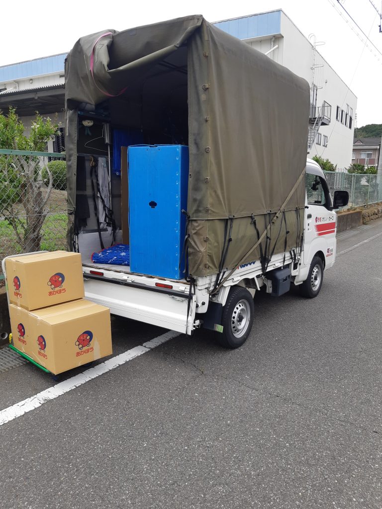 長野県長野市で引越し荷物を搬入中の赤帽車。ハンガーボックス使用、ダンボールと台車。