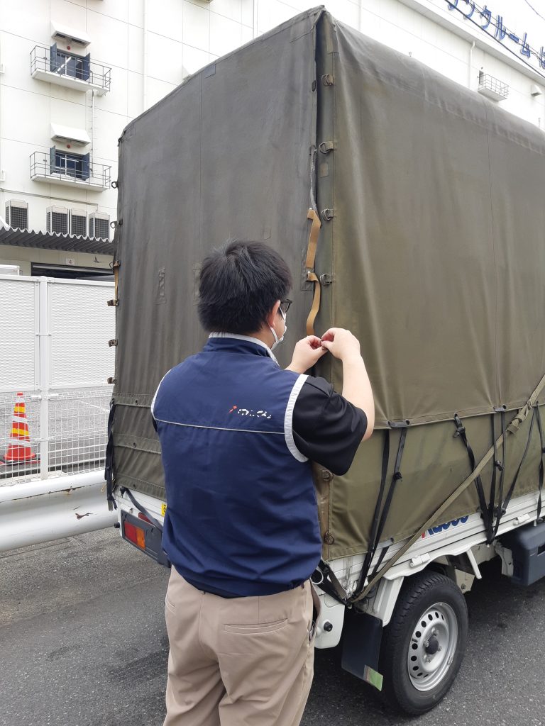 東京都大田区平和島で納品完了後、赤帽車の荷台を確認するスタッフ。